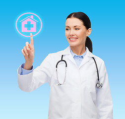 Image showing smiling female doctor pointing to hospital sign