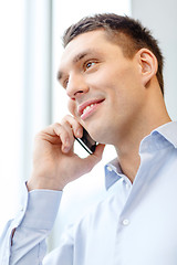 Image showing smiling businessman with smartphone in office