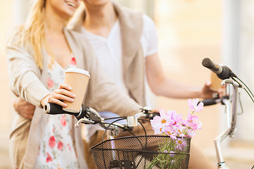 Image showing couple holding coffee and riding bicycle