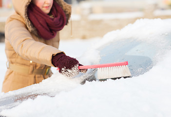 Image showing woman cleaning snow from car back window