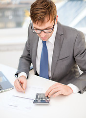 Image showing businessman with computer, papers and calculator