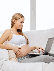 Image showing smiling pregnant woman with laptop computer