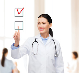 Image showing smiling female doctor pointing checkbox