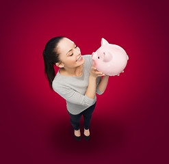 Image showing happy woman looking at piggy bank