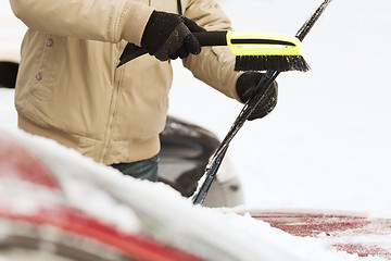 Image showing closeup of man cleaning snow from car