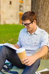 Image showing teenager reading book with take away coffee