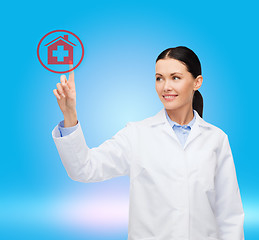 Image showing smiling female doctor pointing to hospital sign