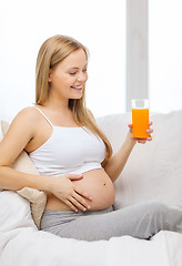 Image showing happy pregnant woman with fresh orange juice
