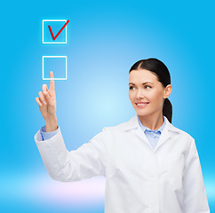 Image showing smiling female doctor pointing to checkbox