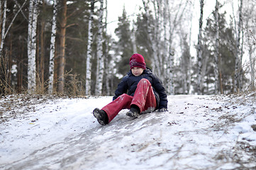 Image showing the teenage boy rides from a hill in the snow-covered wood.