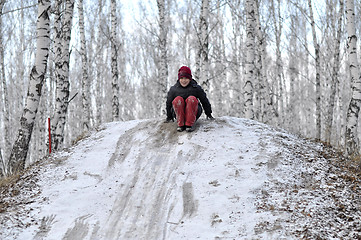 Image showing the teenage boy rides from a hill in the snow-covered wood.