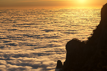 Image showing Silhouette of rocks and sea in sunlit clouds at sunset