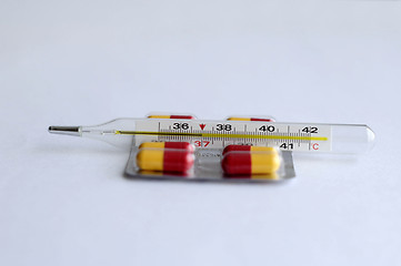 Image showing The increased temperature on a thermometer and pills.