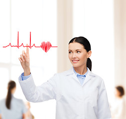Image showing smiling female doctor pointing to cardiogram
