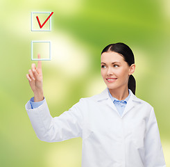 Image showing smiling female doctor pointing to checkbox