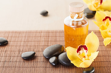 Image showing essential oil, massage stones and orchid flowers