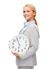 Image showing smiling businesswoman with wall clock