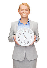 Image showing smiling businesswoman with wall clock