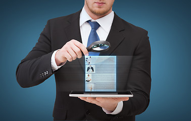 Image showing businessman hand holding magnifier over tablet pc