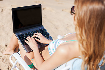 Image showing girl looking at laptop on the beach