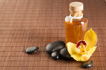 Image showing essential oil, massage stones and orchid flower