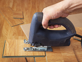 Image showing Master using an electric jigsaw saws laminated panel