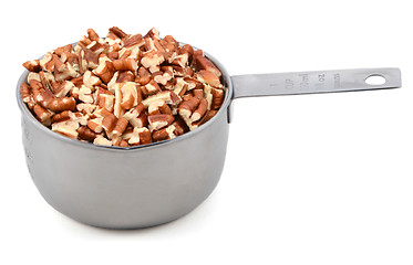 Image showing Chopped pecan nuts in a metal cup measure