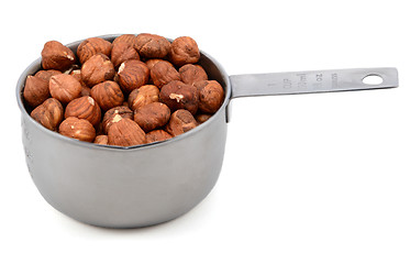 Image showing Whole hazelnuts in a metal cup measure