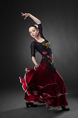 Image showing young woman dancing flamenco on black