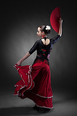 Image showing young woman dancing flamenco with fan on black
