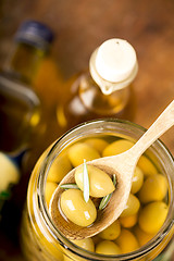 Image showing Close up green olives in bank,  bottle of olive oil, rosemary