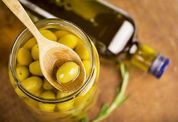 Image showing Close up green olives in bank,  bottle of olive oil, rosemary