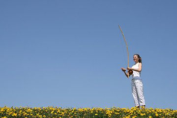 Image showing Girl playing berimbau in spring meadow