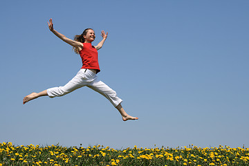 Image showing Girl flying in a jump over flowering field