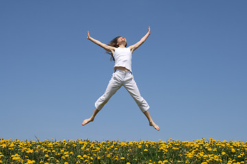 Image showing Smiling girl jumping in flowering meadow