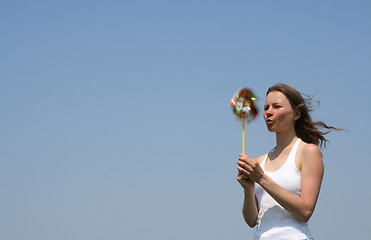 Image showing Young woman blowing a colorful pinwheel