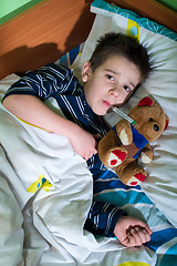 Image showing Sick child in bed with teddy bear