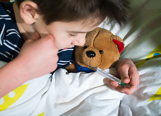 Image showing Sick child in bed with teddy bear