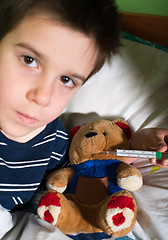 Image showing Sick child in bed with teddy bear