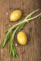 Image showing olives and rosemary on a wooden background