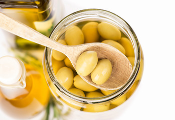 Image showing Close up green olives preserved in bank, bottle of olive oil, rosemary