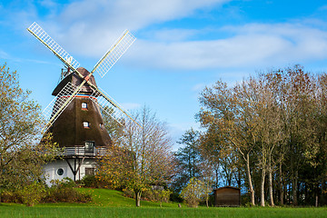 Image showing Traditional wooden windmill in a lush garden