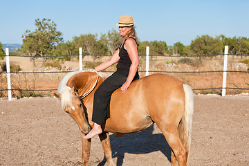 Image showing young woman training horse outside in summer