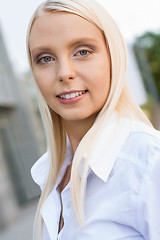 Image showing attractive young successful smiling business woman standing outdoor 