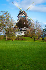 Image showing Traditional wooden windmill in a lush garden