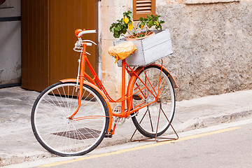 Image showing orange ladies bicycle with flowers decoration