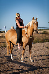 Image showing young woman training horse outside in summer