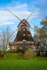 Image showing Traditional wooden windmill in a lush garden