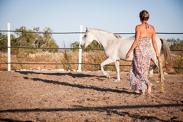 Image showing young woman walking a road with horse