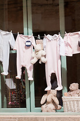 Image showing baby clothing and teddy bear in window